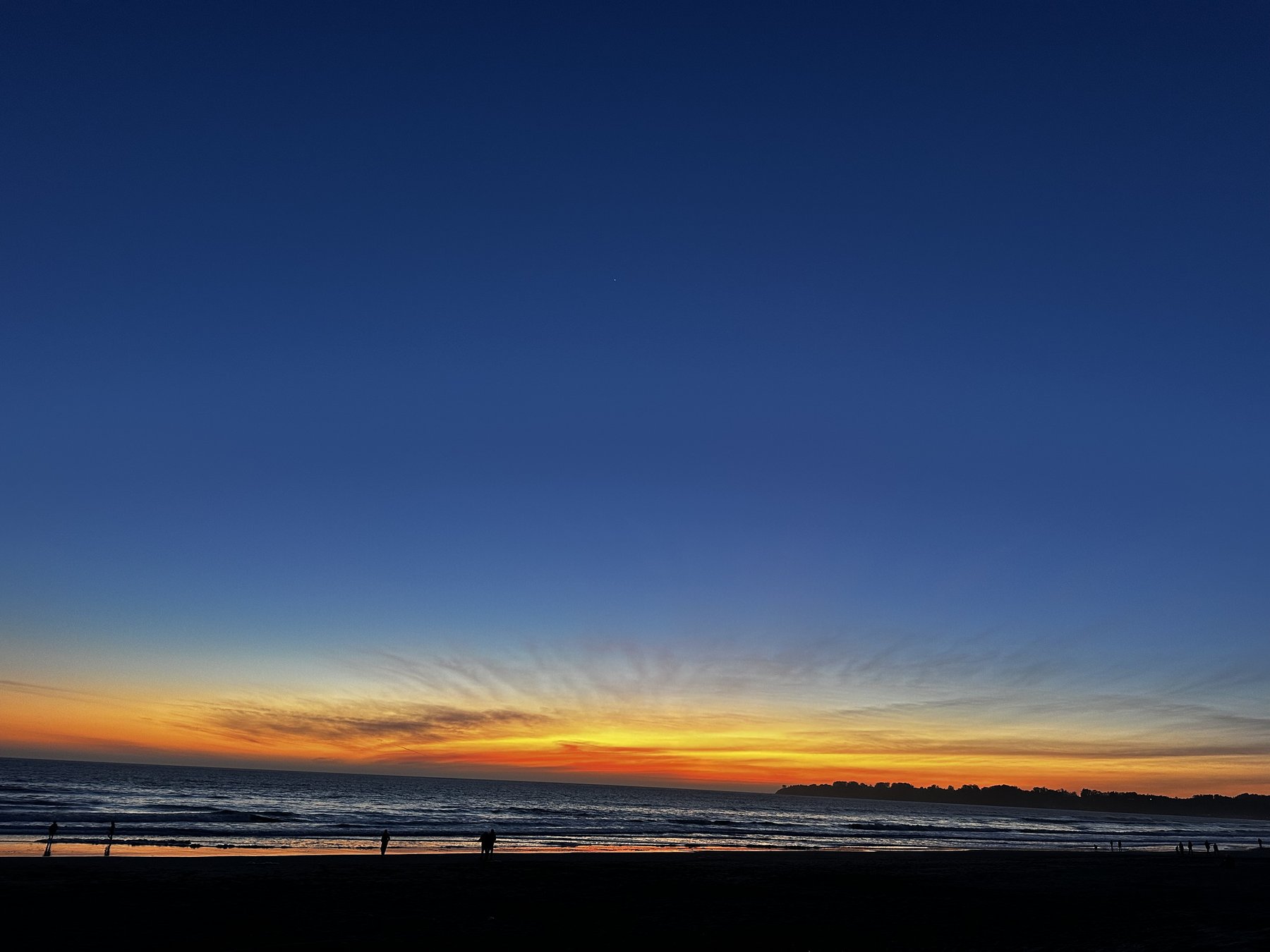 sunset over the ocean, silhouetted figures on the beach