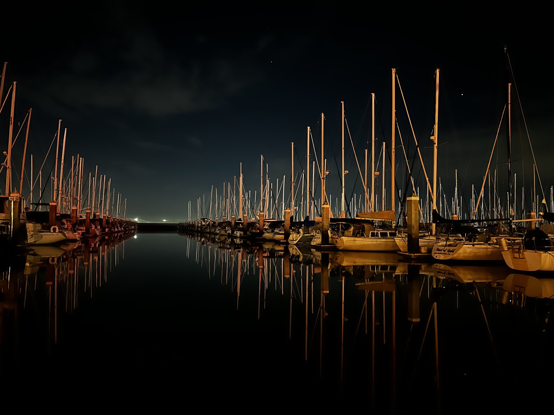 marina at night, boats and masts reflected in still dark water