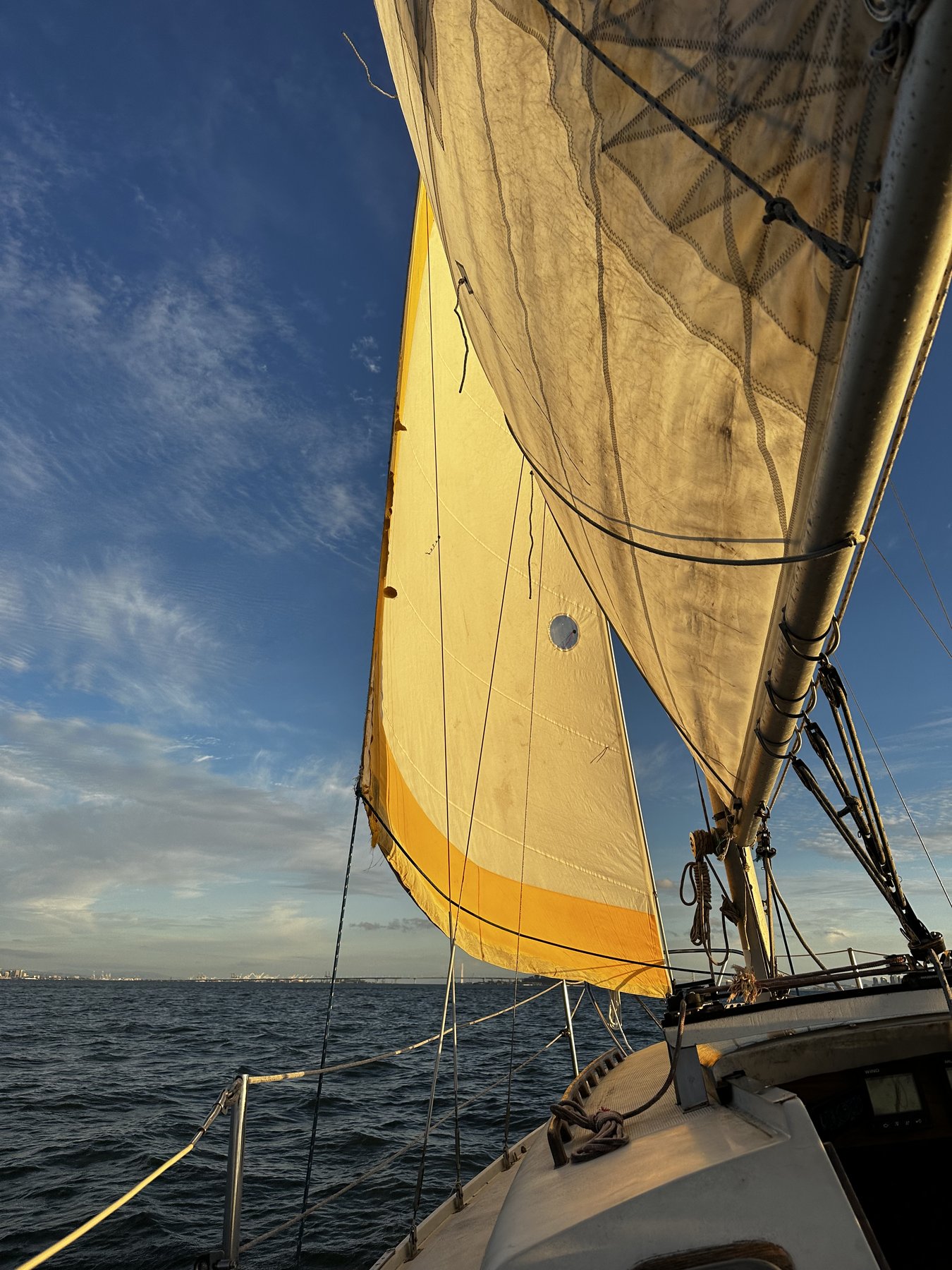 sunlit sail glowing gold against blue sky