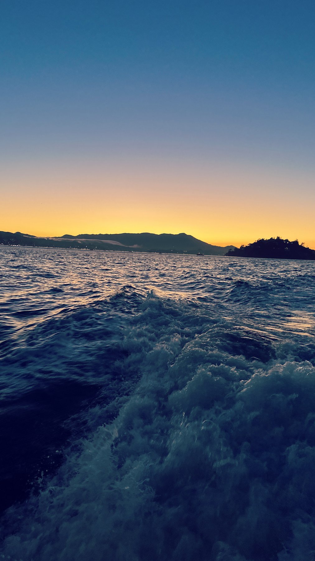 boat's wake at dusk, colorful sky reflected in water