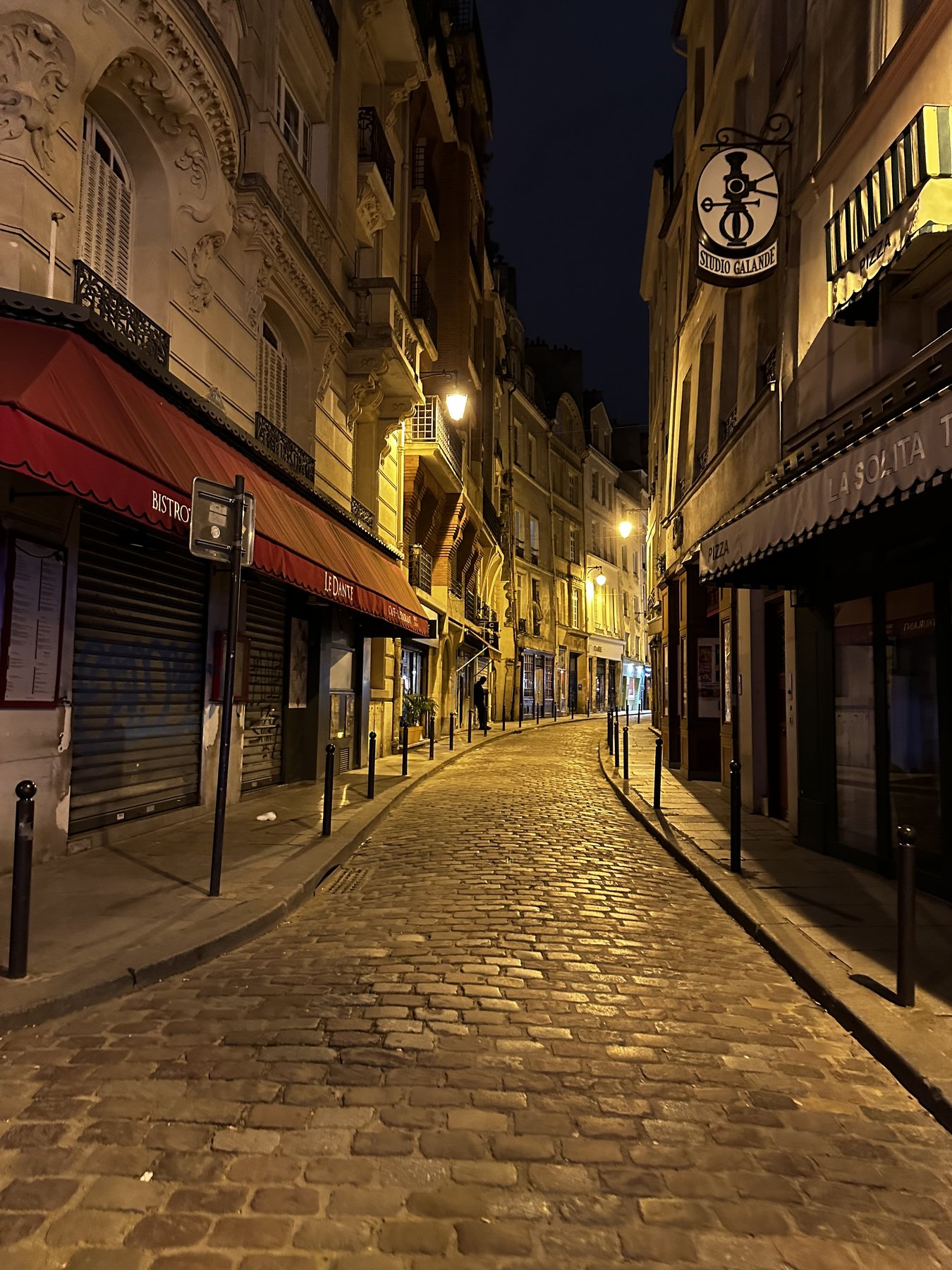 a quiet european street at night, warm lamplight